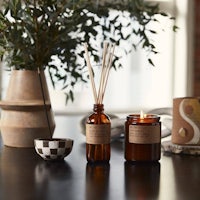 reed diffuser on a table next to a potted plant